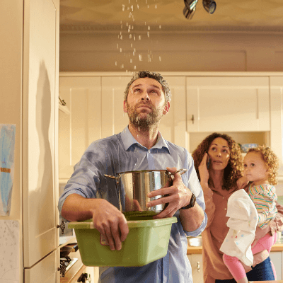 Worried man holding saucepan to catch water leaking from the ceiling in the kitchen